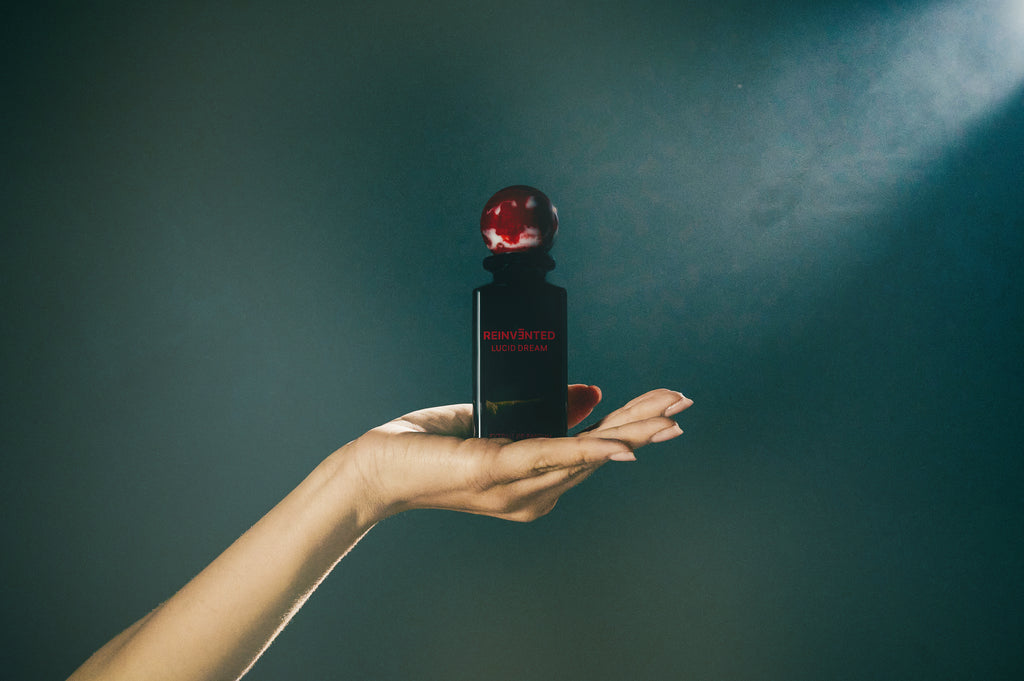 lucid dream perfume bottle by Reinvented Parfums, niche fragrance saffron rose oud, luxury unisex perfume flatlay, dreamy surreal perfume imagery